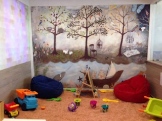 Salinity. Salt Room With Many Kids Toys And Bean-Bag Chairs On The Ground. The Back Wall Is A Mural Painted Of What Appears To Be A Forrest.