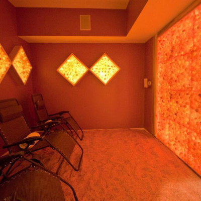 Three Lounge Chairs In A Himalayan Salt Room With Four Diamonded Salt Panel Décor And A Salt Panel Wall Back Lit By Led Lights.