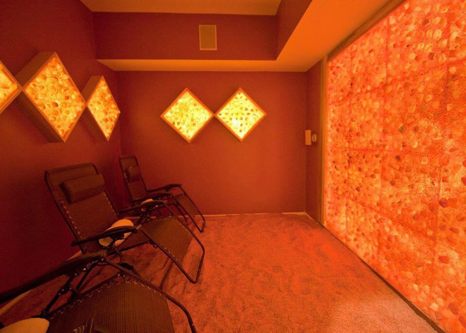 Three Lounge Chairs In A Himalayan Salt Room With Four Diamonded Salt Panel Décor And A Salt Panel Wall Back Lit By Led Lights.