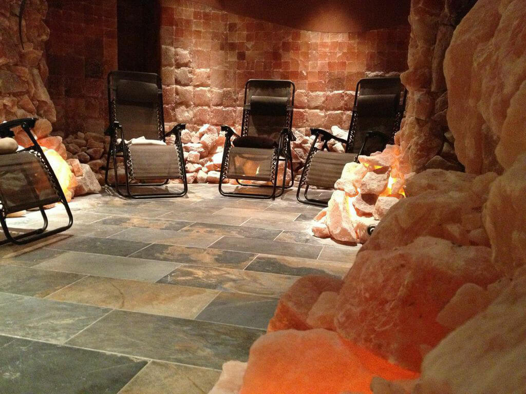 Bien Soigne. Four lounge chairs in dimmly lit pink salt room.