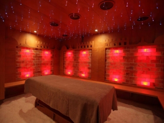 Esagono Italy. Spa Table In Middle Of Salt Room Illuminated By Red Lights.