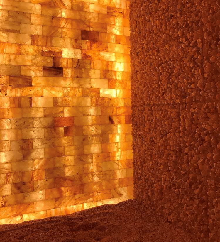Reflexology by Madalyn. Dimly lit salt room with salt tile wall illuminating the room.