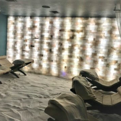 Five reclining chairs on a salt-covered with a salt stone wall backlit by white lighting at the Dolce Organic Salon in Middleburg Heights, Ohio