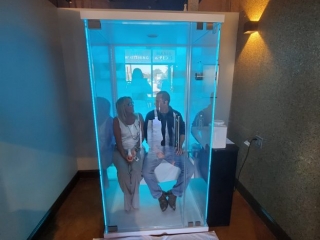 Energy Spa And Tanning. Glass Salt Chamber With Man And Woman Inside. Lit By A Blue Light.