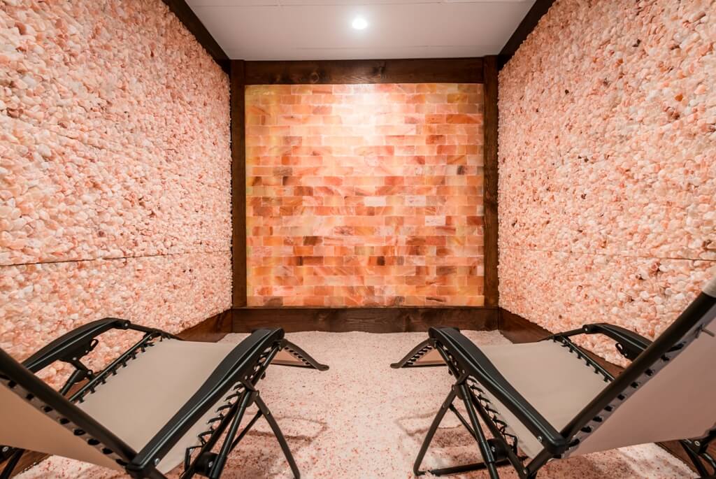 Two Lounge Chairs On A Bed Of Salt Surrounded By Two Himalayan Salt Panel Walls And A Salt Brick Wall At The Intown Salt Room - Atlanta (Grant Park), Georgia.
