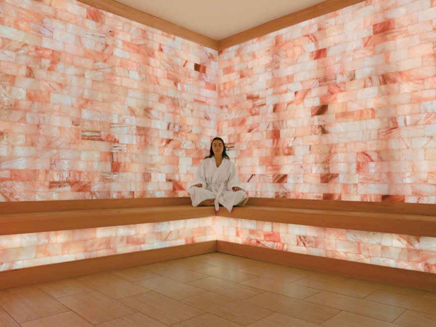 Jw Marriott Miami turnberry resort & spa. Woman is sitting in corner of bench surrounded by pink salt tiles on the wall.