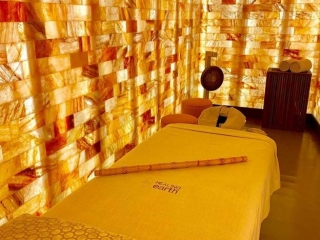 Sulha Spa At Kudadoo. View Of Massage Bed With Bamboo Stick On It. Behind The Bed Is A Gong And Chairs.