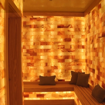 Salt therapy room with a light wooden bench and four pillows surrounded by LED backlit salt panel walls at The Ritz Carlton Spa - Charlotte, North Carolina.