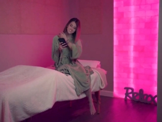 Woman In A Green Robe Sitting On A Cushioned Table Covered By A White Blanket With A Pink Backlit Salt Stone Wall And Square Salt Stone Decor At The Premier Day Med Spa In Hallandale Beach, Florida
