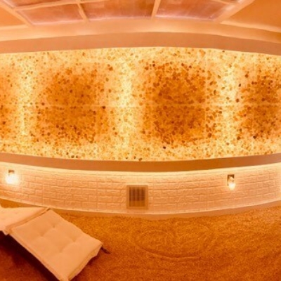 A White Cushioned Chaise On A Himalayan Salt-Covered Floor With Led Lit Salt Walls And Beach Wallpaper.