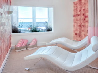 Salt Live Energized At The Sound View In Greenport. Two White Beds In Naturally Lit Room Face Pink Salt Wall.