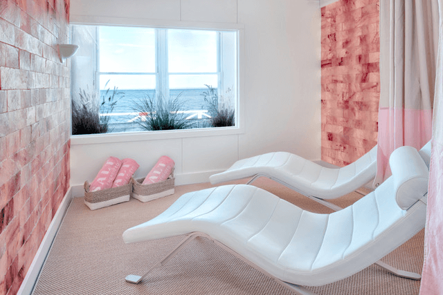 Salt live energized at the sound view in Greenport. Two white beds in naturally lit room face pink salt wall.