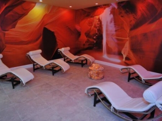 The Salt Station. 5 Lounge Chairs Facing Each Other In Large Spa Room. Walls Are Completely Covered In Pictures Of Red Rock Caves.
