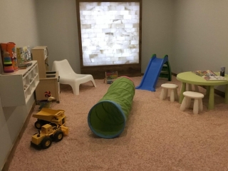 Salt-covered floor with children's toys and a white backlit square salt stone wall at the Saltastic in Kemptville, Ontario