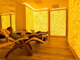 Two Women Relaxing In Reclined Chairs In A Room Surrounded By Yellow Backlit Himalayan Salt Stone Walls At The Silver Solutions Medspa In Pittsfield, Massachusetts.