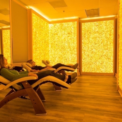 Two women relaxing in reclined chairs in a room surrounded by yellow backlit Himalayan salt stone walls at the Silver Solutions MedSpa in Pittsfield, Massachusetts.