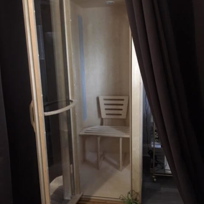White salt booth with a wooden foot mat son a grey vinyl floor surrounded by brown curtains on each side.