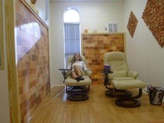 Dead Sea Salt Room. Bright Room With Wooden Floors. A Woman Lays Back In One Of The Two Lounge Chairs In The Room.