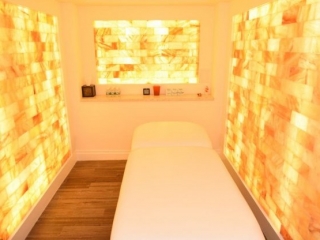 The Juhi Center. Massage Bed. Behind Bed Is A Shelf With Different Oils And Minerals On It.