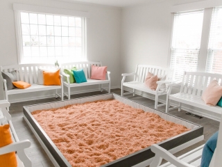 Seven white benches with pillows surrounded a Himalayan salt-covered rectangular pen a the The Salt House of Worthington in Worthington, Ohio