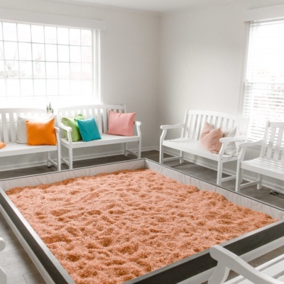 Seven white benches with pillows surrounded a Himalayan salt-covered rectangular pen a the The Salt House of Worthington in Worthington, Ohio
