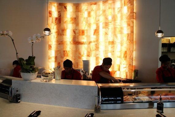 Red Salt Chophouse & Sushi. View of 4 cooks making sushi behind the counter. Behind them all, is a large tile formation on the wall.