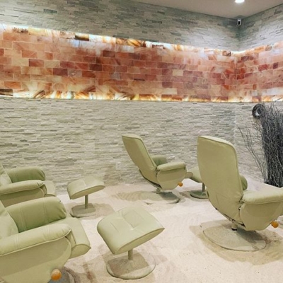 Four White Cushioned Chairs With A Foot Rest On A White Salt Covered Floor With A White Offset/Staggered Salt Brick Wall And A Himalayan Salt Panel Centered Going Around The Room On The Wall In The Salt Nest - Plantation, Florida.