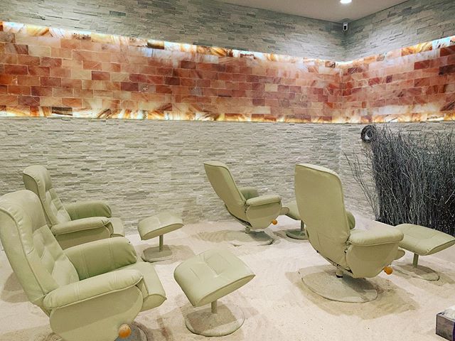 Four White Cushioned Chairs With A Foot Rest On A White Salt Covered Floor With A White Offset/Staggered Salt Brick Wall And A Himalayan Salt Panel Centered Going Around The Room On The Wall In The Salt Nest - Plantation, Florida.