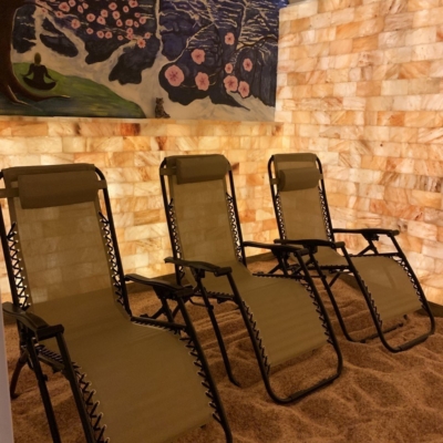 Three reclining chairs in salt room with paintings of trees on wall directly behind the chairs at the Above and Beyond Yoga Center in Mobile, Alabama.