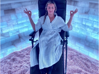 Salt &Amp; Sweat. Woman Relaxes In Lounge Chair While Meditating. While Doing This, She Is In The Corner Of A Salt Room With Illuminated Walls.
