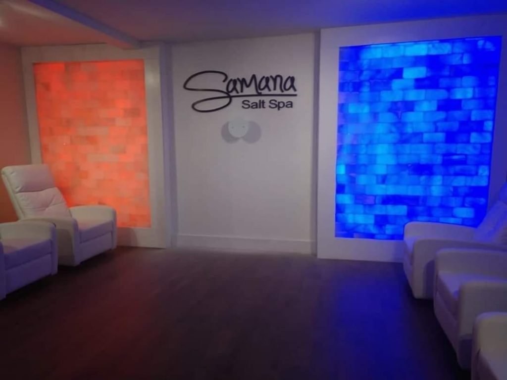 Samana Salt Spa. View Of Front Of Spa. Left Side Of The Wall Has Orange Salt Tiles And The Right Side Has Blue. In The Middle Of The Wall, Is The Company Logo Spelling Out &Quot;Samana Salt Spa&Quot;