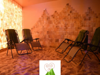 Prana Salt Cave. Four Lounge Chairs With Green Towels Draped Over Them, Face Each Other In Salt Room. Text And Logo Over Picture Read: Prana Salt Cave.