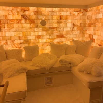 A white booth with pillows with a salt-covered floor and backlit salt stone walls at a private residence in St. Louis, Missouri.