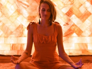 Prana Salt Cave. Woman Sitting On The Salt Room Floor Appearing To Be Meditating.