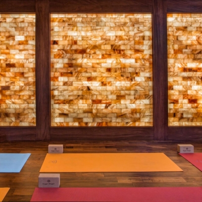 Six Yoga, Mats Two Red, Two Orange, And Two Blue, All With Yoga Blocks On A Wooden Floor In Front A Himalayan Salt Stone Wall.