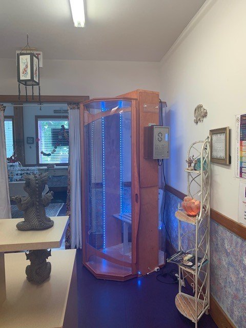 Salt therapy booth with blue LED lighting on a dark wooden floor with decor around the room at the Mystic Bayou Holistic and Alternative Health in Slidell, Louisiana