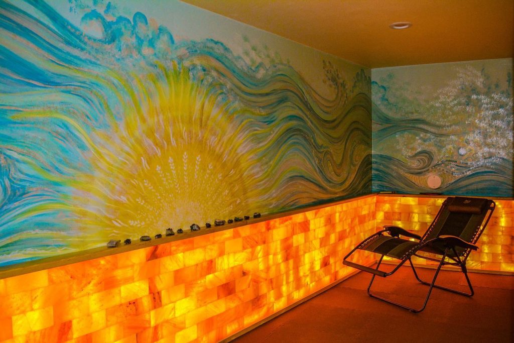 BeWell Marquette. lounge chair in salt room with sun and ocean waves painted on the walls
