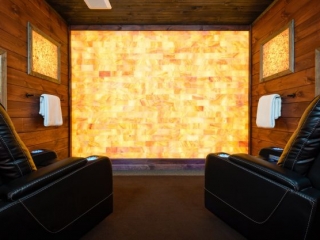 Larose Muscular Therapy. Two Large Black Massage Chairs Sit In Spa Room While Facing Tiled Wall.