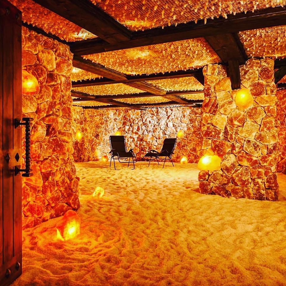 Salt Cave Santa Barbara. Large salt room with different areas separated by salt rock dividers. Room is illuminated by salt rocks scattered around the room.