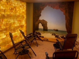 New Genisis Health. 5 Lounge Chairs Inside Of Salt Room While Facing A Mural Of The Ocean