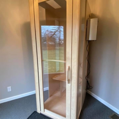 Light wooden and glass salt booth on a light grey carpet with a dark grey foot mat in a light grey room in Seneca Chiropractic and Family Wellness in Liverpool, New York