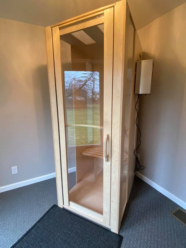 Light wooden and glass salt booth on a light grey carpet with a dark grey foot mat in a light grey room in Seneca Chiropractic and Family Wellness in Liverpool, New York
