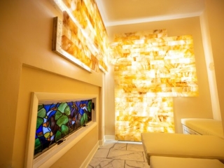 Empowered Healing. Spa Room With Stained Glass, And Brightly Lit Stones On Wall.