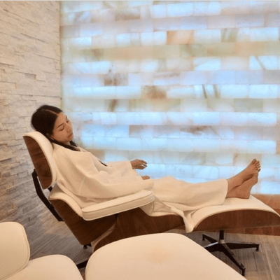 Halo Spa &Amp; Salt. Woman Relaxes In Lounge Chair Inside Of Bright, White Salt Room.