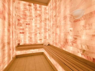 The Henderson Beach Resort &Amp; Spa. Narrow Spa Room With Wooden Bench Wrapped Around The Room. All Of The Walls Are Very Light Colored Salt Tiles.