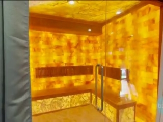 Lit Lab Wellness Center. Large Glass Corner Salt Room With Yellow Lighting And Bench Inside