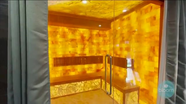 LIT Lab Wellness Center. Large glass corner salt room with yellow lighting and bench inside
