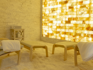 Natural Healing Day Spa. Brightly Lit Salt Room With White Salt. Three Lounge Chairs Sit Inside Of The Room.