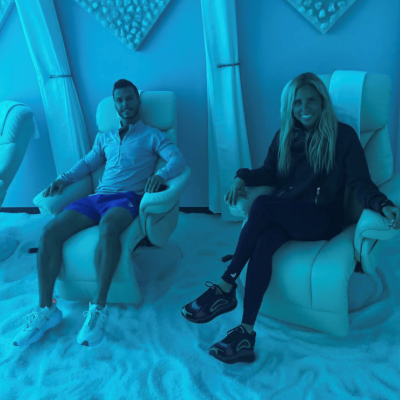 Woman and man in a white cushioned chair relaxing on a white salt-covered floor smiling at the NexGen Fitness in Buffalo, New York
