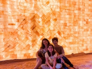 Prana Salt Cave. Two Women And Young Girl Sit Together On The Salt Room Floor.